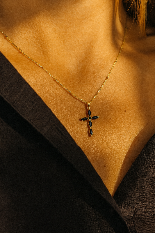 Necklace with a cross pendant on a person wearing a black garment.