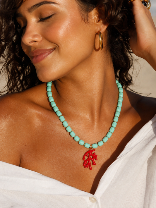 Woman wearing a turquoise necklace with a red coral pendant