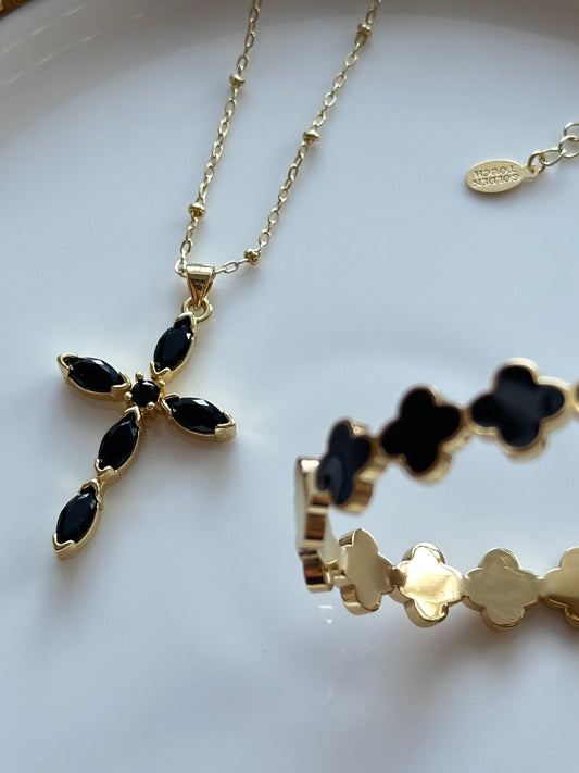 Gold necklace with black pendant on a white surface