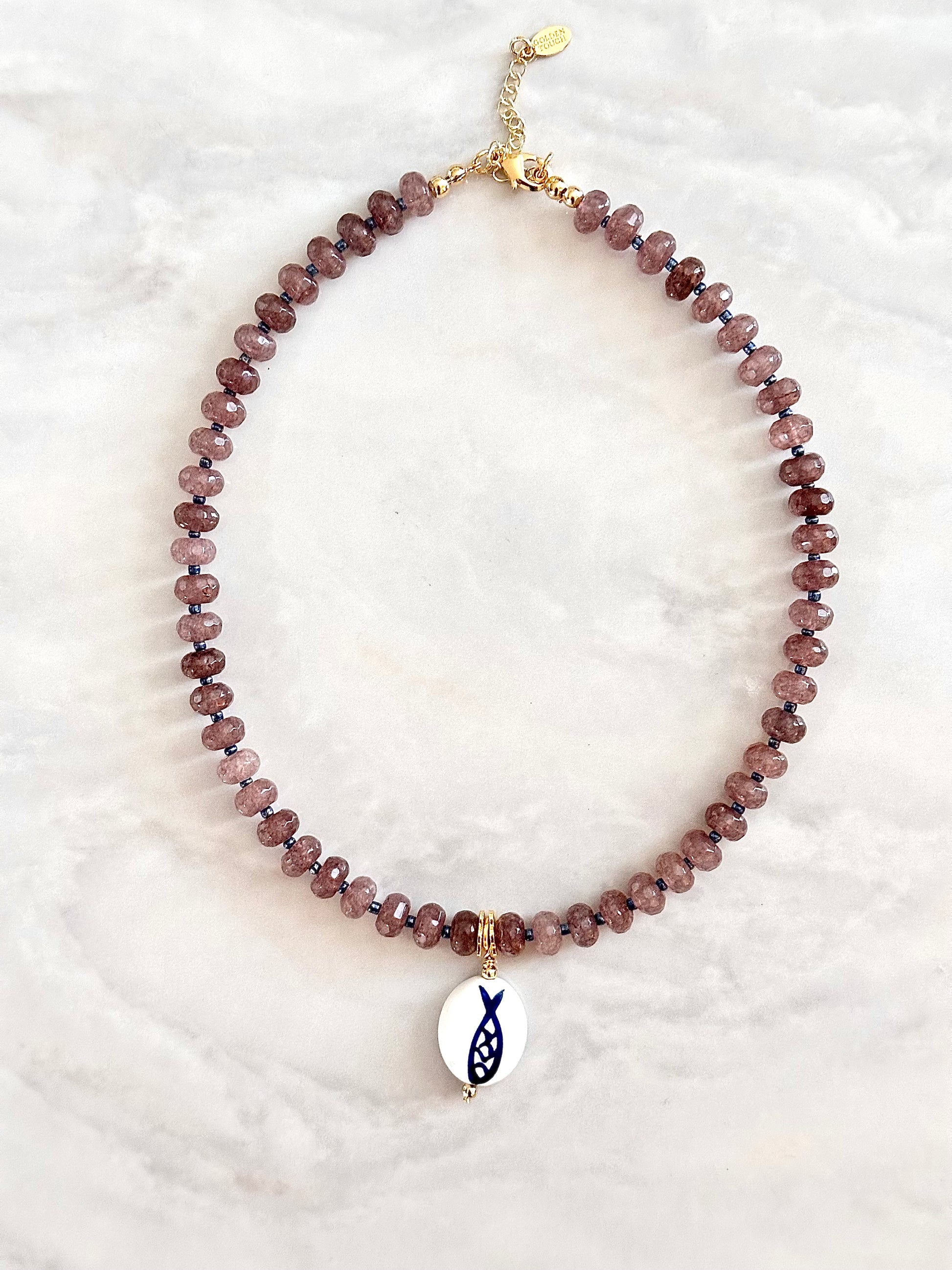 Necklace with purple beads and a fish charm on a white background