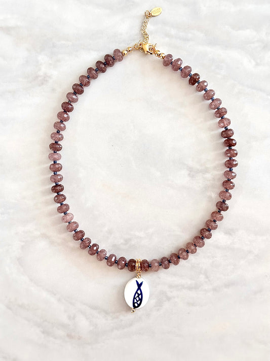 Necklace with purple beads and a fish charm on a white background