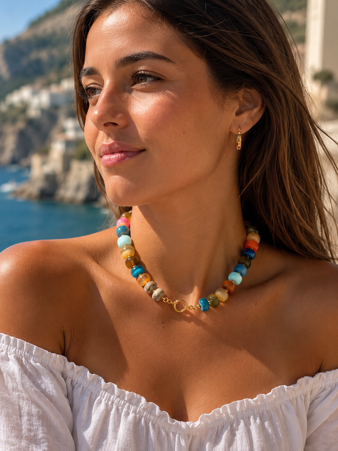 Young woman wearing a premium acrylic beaded colorful necklace with front toggle clasp wearing a white off shoulder top on vacation 