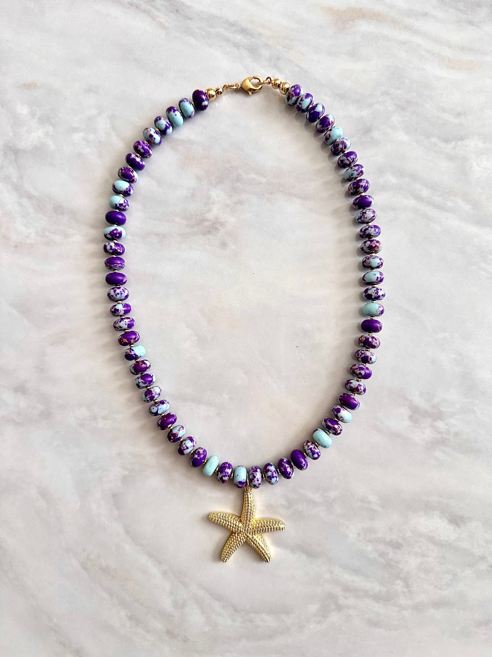 Necklace with purple beads and a gold starfish pendant 