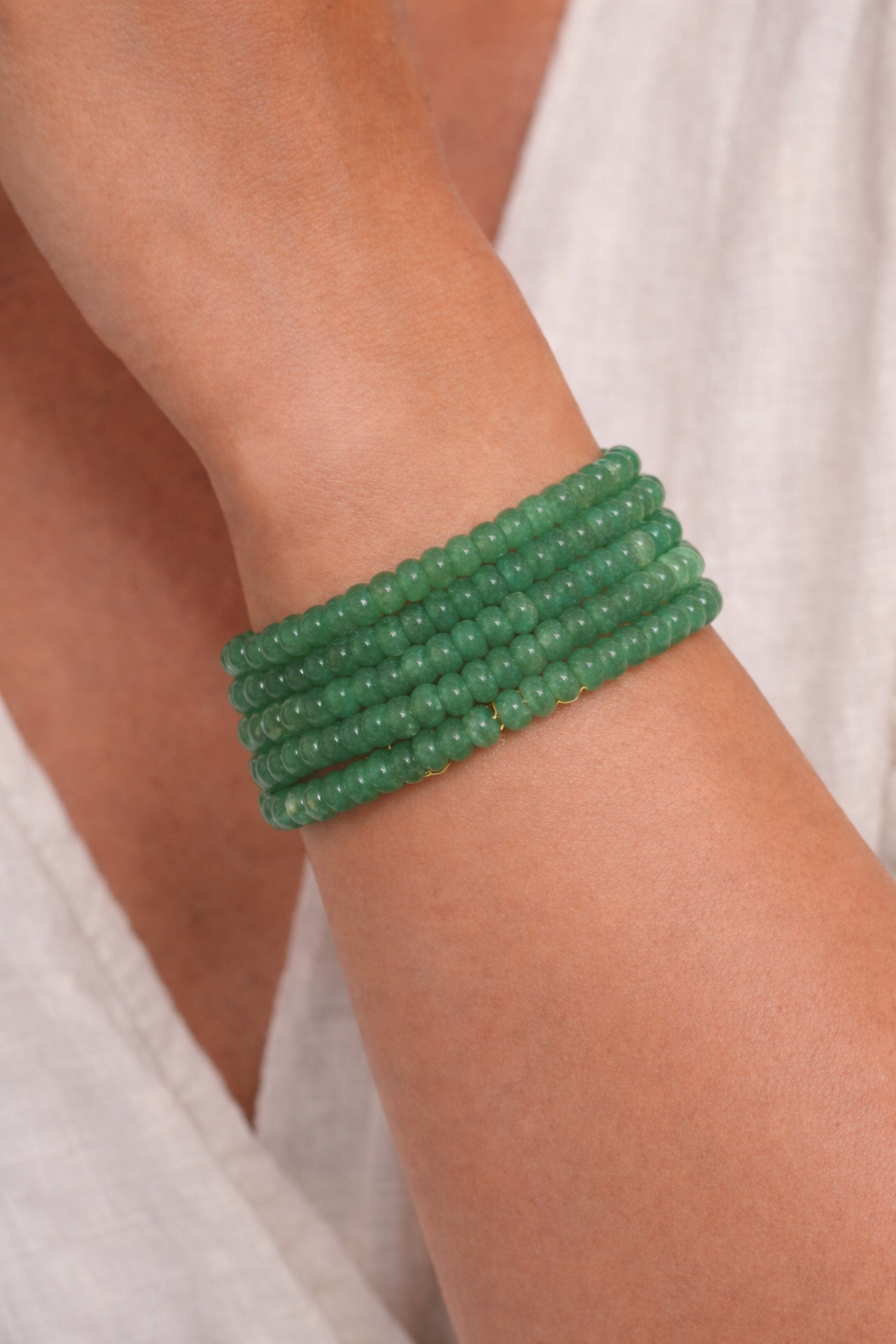 Green beaded bracelet on a wrist with a white background