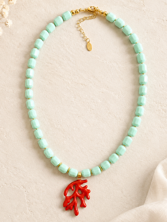 Necklace with turquoise beads and a red coral pendant on a beige background